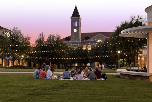 Students sitting in a circle on the grass within the Campus Commons