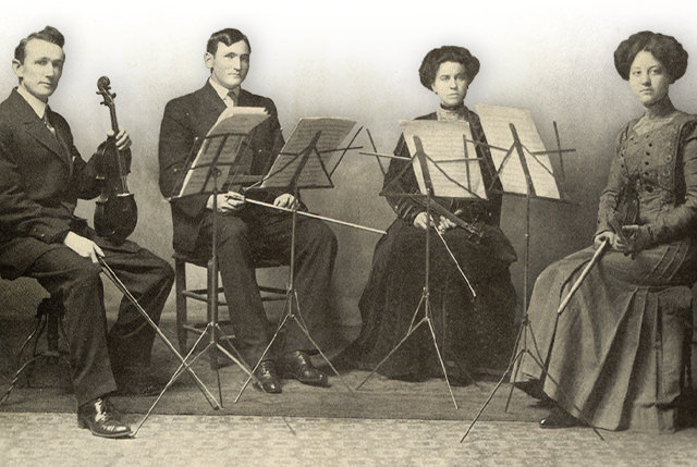 A student quartet, seated with their instruments and music stands