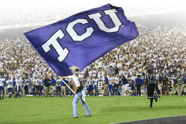 A Ranger waves the TCU flag on the football field